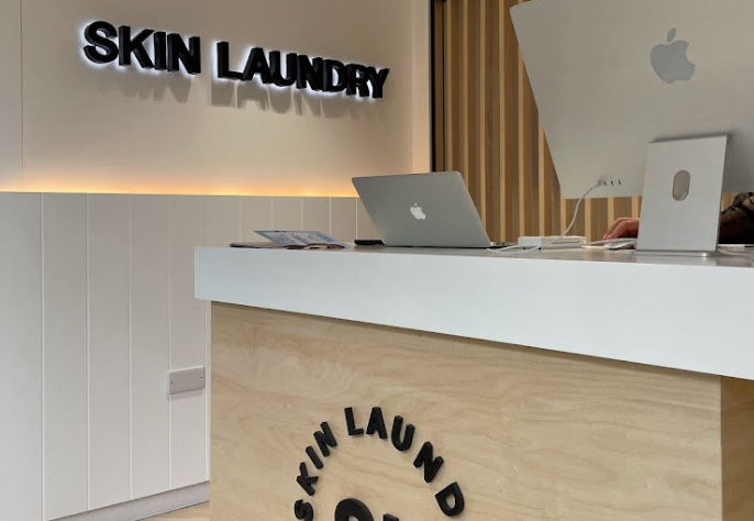 Modern Skin Laundry UAE reception area with branded front desk and Apple devices.